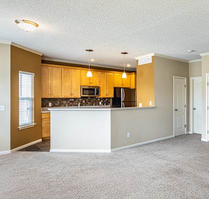 a living room with a staircase and a kitchen in the background