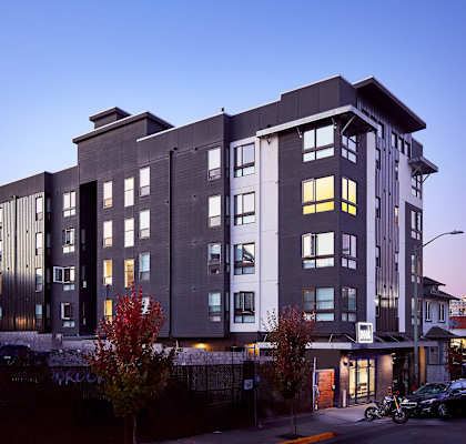 a large apartment building at dusk with cars parked in front of it