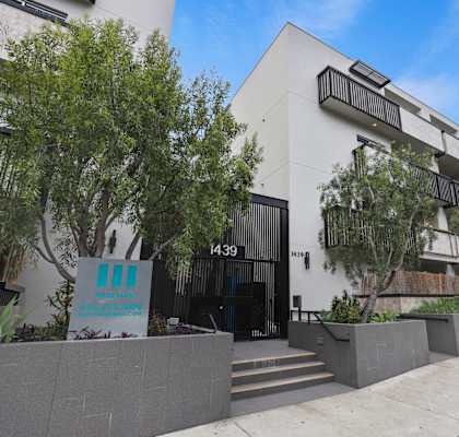 a white apartment building with trees in front of it