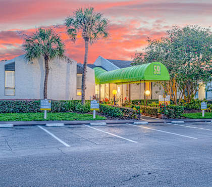 A parking lot in front of a building with a green awning and the number 59 on it.