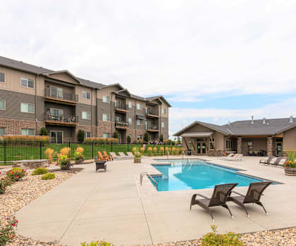 A swimming pool surrounded by lounge chairs and apartment buildings.