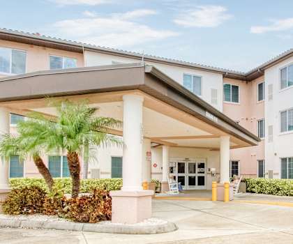 Exterior of Holy Cross Manor II with fence and lush palm trees