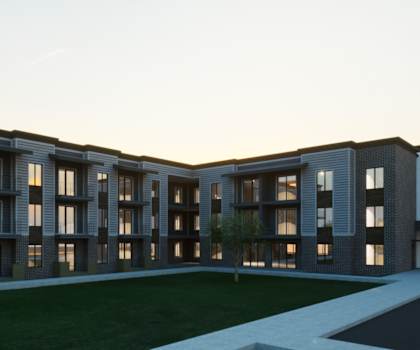 A modern building with a long row of windows and a grassy area in front.