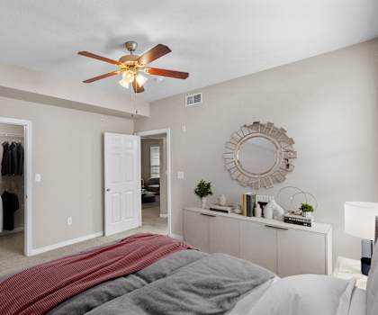 a bedroom with a large bed and a ceiling fan at The Clairborne Apartment Homes, Grand Prairie, TX, 75050