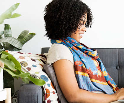 Woman sitting on a couch using a laptop computer  at Charbonneau Apartments in Seattle, WA 98101