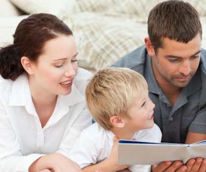 Image showing family of 4 reading a book together