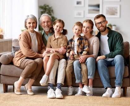 A family of five is sitting together on a couch in a living room.
