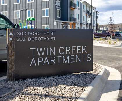 A sign for Twin Creek Apartments is in front of a building.