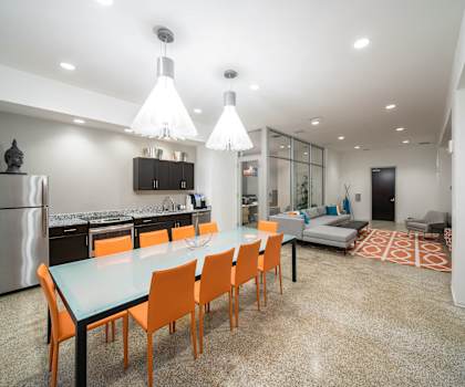 a long dining table with orange chairs in a room with a kitchen and living room at The Equitable Building, Des Moines, IA, 50309