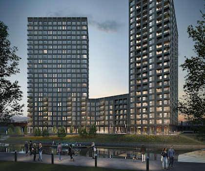 A modern building with a glass facade is surrounded by a park with people walking and sitting on benches.