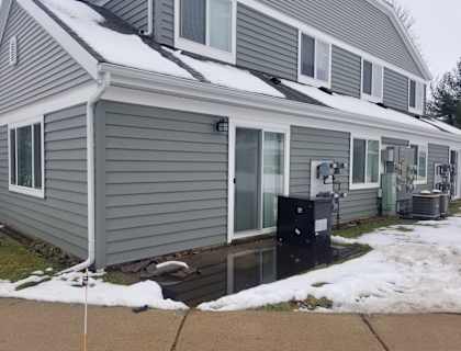 A house with a grey siding and a black mailbox.