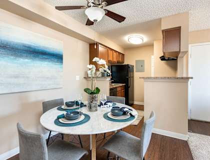 a dining area with a table and chairs and a ceiling fan