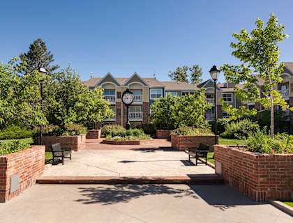 a courtyard with benches and a clock in front of an apartment building