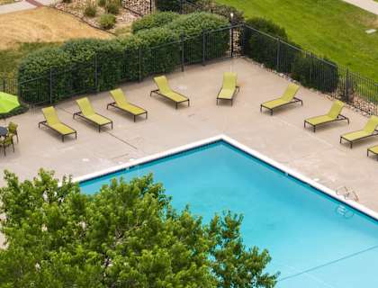 a swimming pool with yellow and green lounge chairs around it