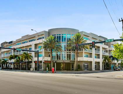 a large building on the corner of a street with palm trees