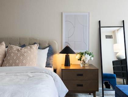 a bedroom with a bed and a nightstand and a mirror