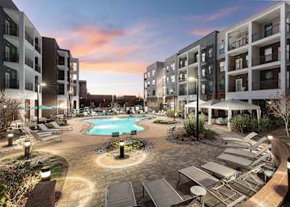 an apartment complex with a swimming pool at dusk