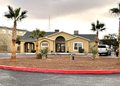 A building with a red border around it and palm trees in front.