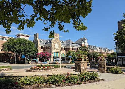 a square with a fountain and buildings in the background