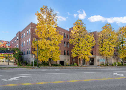 a red brick building on a street corner with yellow trees