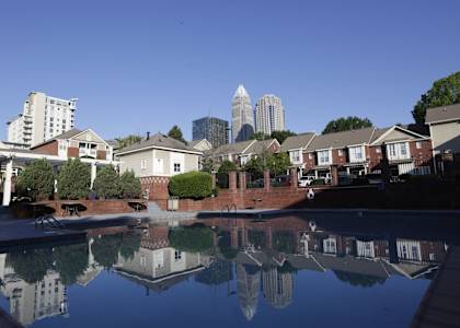 A pool in a residential area with a city skyline reflected in the water.