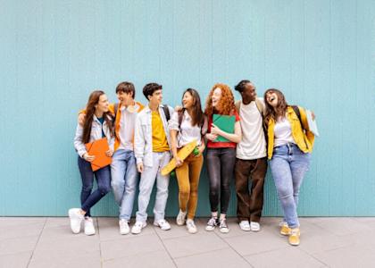 A group of seven people stand in front of a blue wall.