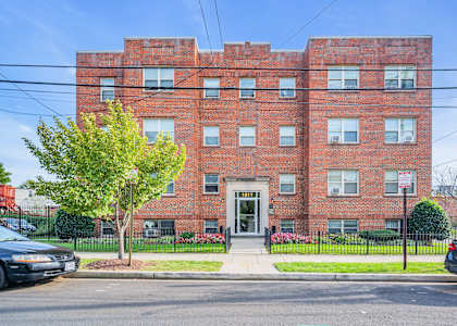 a red brick apartment building with a sidewalk in front of it