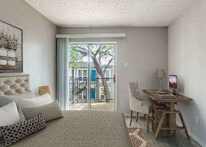 A bedroom with a bed, desk, and chair.