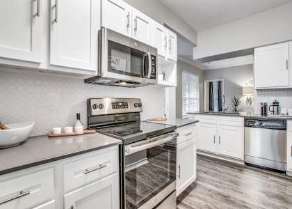 North Dallas TX Apartments- Spacious Modern Kitchen With Gray Granite Countertops, White Cabinets, and Stainless Steel Appliances