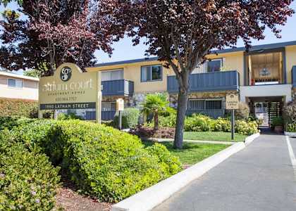 A building with a sign that says "atrium court apartment" in front of it.