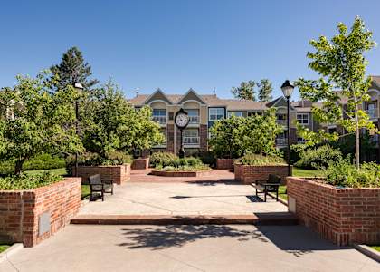a courtyard with benches and a clock in front of an apartment building