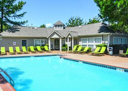 A pool with lounge chairs and a house in the background at Southaven Pointe Apartments, Southaven