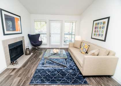 View of living room showing vaulted ceiling, wood burning fireplace, and personal balcony.