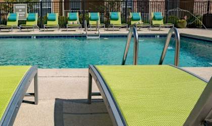 a pool with green and yellow lounge chairs