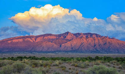 A large cloud hovers over a mountain range.
