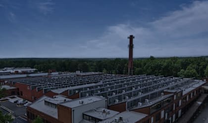 A large building complex with a tall chimney in the distance.