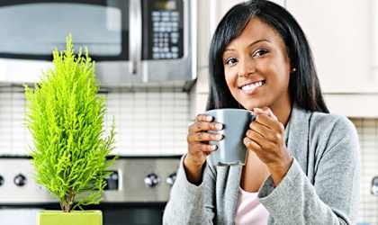 a woman holding a cup of coffee in the kitchen