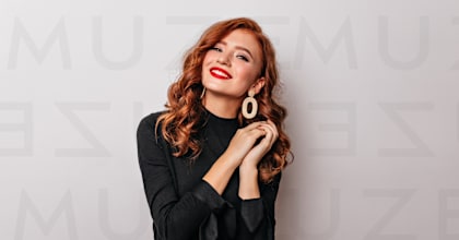 A woman with red hair and a black top is wearing large hoop earrings.