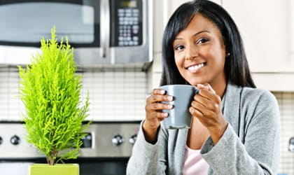 a woman holding a cup of coffee in the kitchen