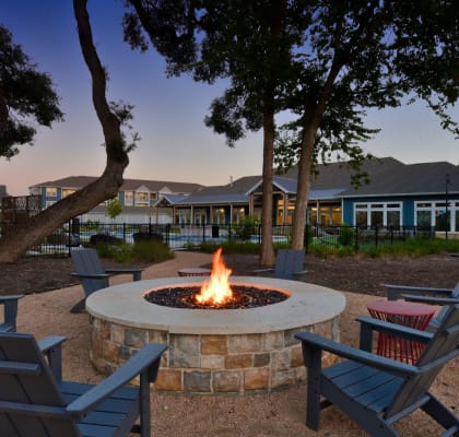 a fire pit with chairs in front of a house