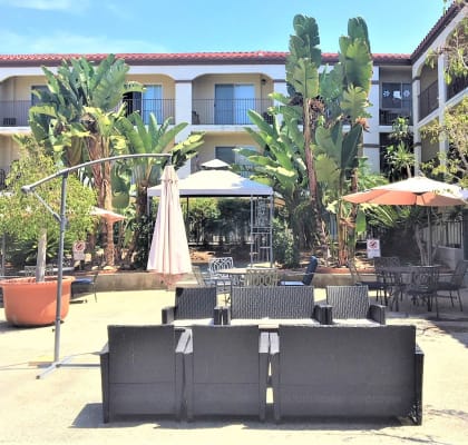 a patio with tables and chairs in front of a hotel