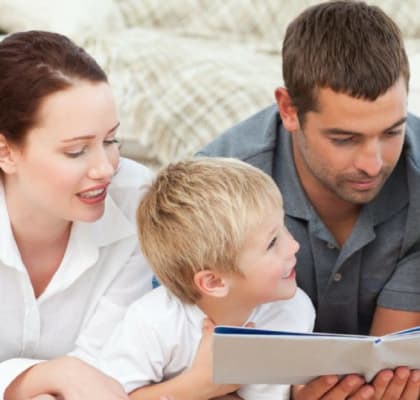 Image showing family of 4 reading a book together