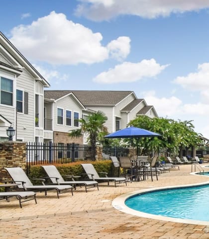 the preserve at ballantyne commons community swimming pool with lounge chairs and umbrellas  at Kingston Crossing Apartment Homes, Bossier City
