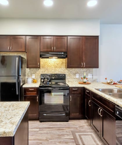 a kitchen with dark wood cabinets and granite countertops at Allora Phoenix Apartments, Phoenix, Arizona