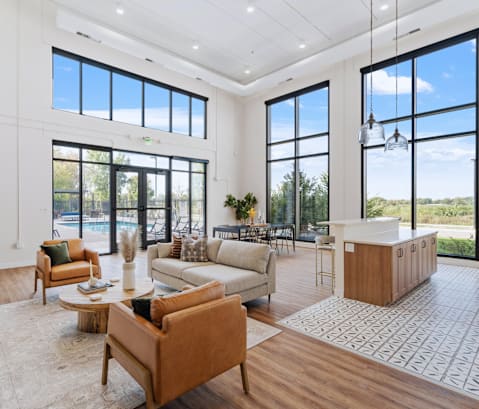a large living room with a kitchen and a pool in the background