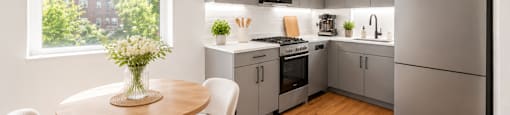 A modern kitchen with a table and chairs by the window.