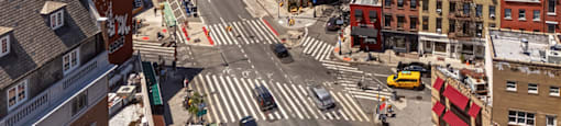 A city street with a crosswalk and a yellow taxi.