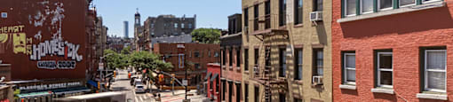 A street view of a city with buildings on either side and a car driving down the road.