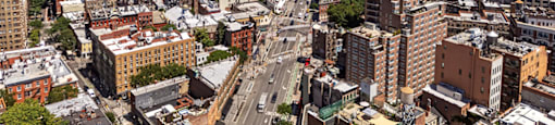 A cityscape with a mix of old and new buildings, a clear blue sky, and a distant skyline.