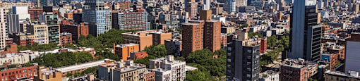 A cityscape with a mix of modern and older buildings under a clear sky.